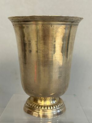 a silver vase sitting on a glass stand on a table