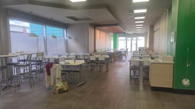 de nombreuses tables et chaises dans une grande pièce dont la porte est verte
