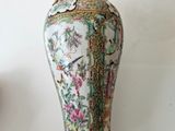 a vase that is sitting on a table with a clock in the background