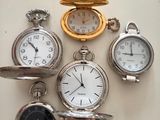 many different types of pocket watches displayed on a table