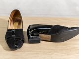 pair of black shoes on a wooden table with a white wall in the background