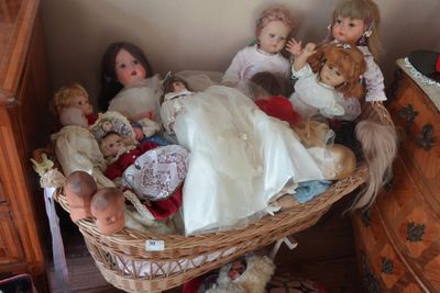 beaucoup de poupées dans un panier posé par terre