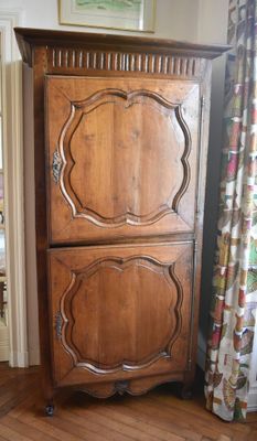 a tall wooden cabinet in the corner of a room
