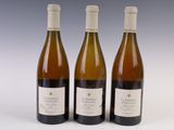 trois bouteilles de vin posées les unes à côté des autres sur une surface blanche