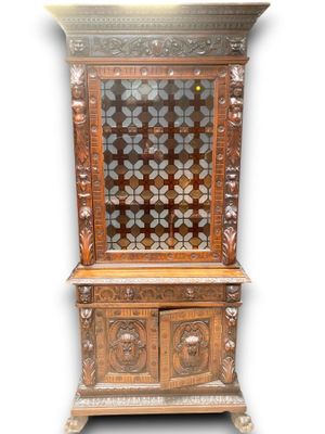une vieille armoire en bois avec des portes vitrées et des sculptures sur la façade