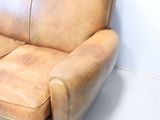 a brown leather couch sitting in the corner of a room