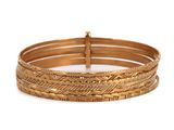 un gros plan sur une pile de bracelets en or sur fond blanc