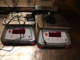 two electronic scales sitting on a metal counter top