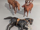 trois figurines représentant des chevaux et un chien posées sur une table