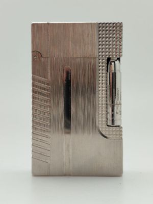 briquet argenté avec un briquet au centre, posé sur une surface blanche