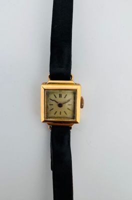 une photo d'une montre plaquée or avec un bracelet en cuir noir