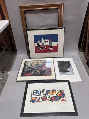 several framed art pieces are on a table in front of a wall
