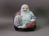 a figurine of a smiling buddha sitting on a cushion
