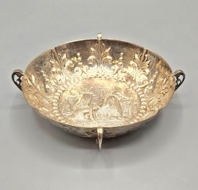 un plat ancien en argent, muni de poignées, sur un fond gris