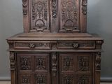 une vieille armoire en bois ornée de sculptures sur le dessus, dans une pièce
