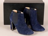 une paire de bottines en daim bleu devant une boîte noire