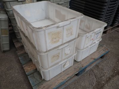 une pile de bacs en plastique posée sur une palette dans un entrepôt