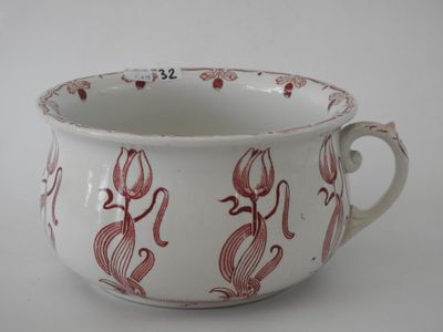a white cup with red designs on it on a white surface