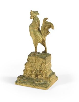 statue en or représentant un coq posé sur un rocher, sur fond blanc