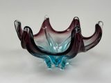un bol en verre violet et bleu posé sur une surface blanche