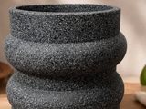 a close up of a black stone vase on a wooden table