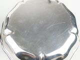 a silver plate on a white table with a spoon and spoon rest