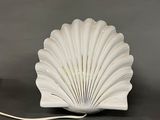 a white shell shaped lamp that is on a table