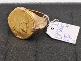 a gold ring with a coin on it and a price tag attached to it