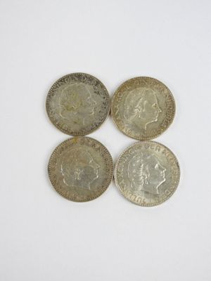Quatre pièces de monnaie britanniques sont disposées en ligne sur une surface blanche
