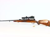 the rifle is laying on a white surface with a scope on it