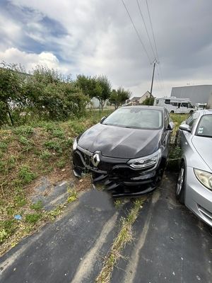 Deux voitures sont garées sur le bord d'une route, près d'une maison.