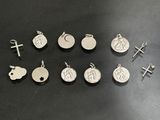 several silver charms and a cross on a black surface