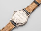 a close up of a watch on a white surface with a black strap
