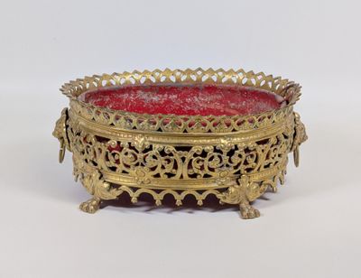 un plateau en or richement décoré, avec un verre rouge au centre