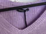 un pull violet orné de fleurs blanches, suspendu à un cintre