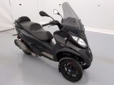 un scooter noir garé dans une pièce aux murs blancs