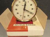 une horloge posée sur une boîte, elle-même posée sur une table