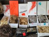 de nombreux types de perruques dans une boîte posée sur un canapé