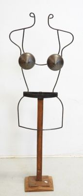 a metal sculpture of a woman ' s face on a wooden stand
