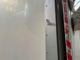 a white truck with a red stripe parked in front of a building