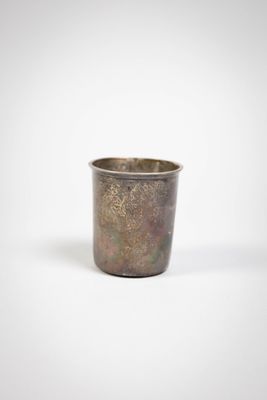 a close up of a metal cup on a white surface