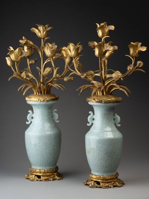 une paire de vases anciens contenant des fleurs, sur fond gris