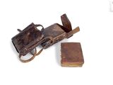 an old book and a leather case on a white surface