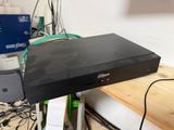 a black dvd player sitting on top of a wooden shelf