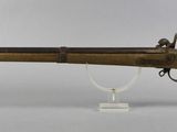 a rifle with a wooden barrel on a stand on a white surface