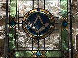 a stained glass window in the corner of a stone wall