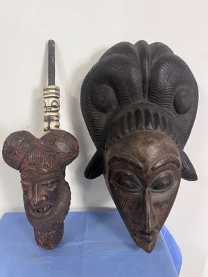 deux masques en bois posés l'un à côté de l'autre sur un socle bleu