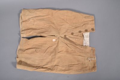 un vieux pantalon avec des boutons, posé sur une surface grise