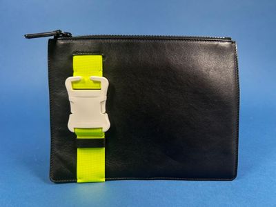 a black purse with a yellow strap and a white buckle