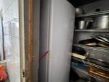 a refrigerator in a kitchen with a bunch of pots and pans on the counter